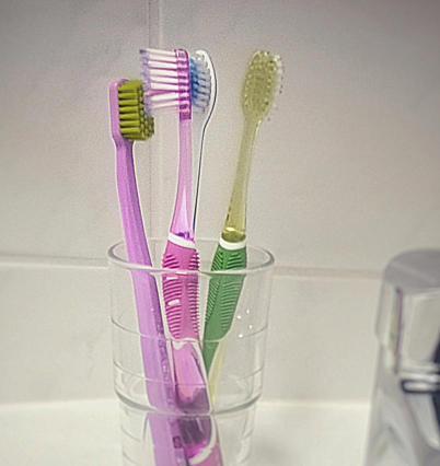 Zahnbürstenhygiene - Zahnbürsten unhygienisch Kopf an Kopf im Glas